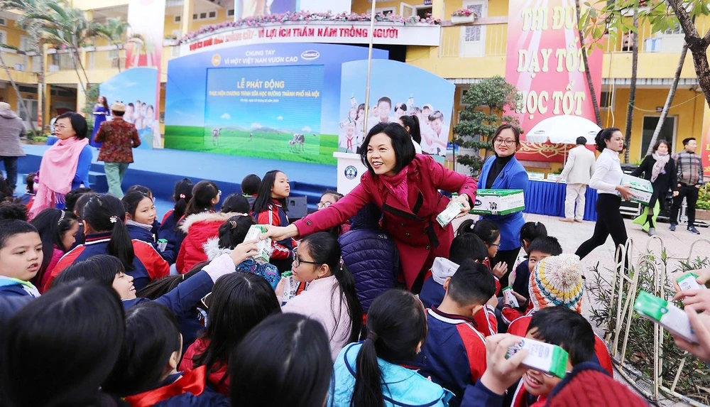 Bà Bùi Thị Hương, Giám đốc Điều hành Vinamilk trao sữa cho các em học sinh tại Lễ phát động thực hiện chương trình Sữa học đường tại thủ đô Hà Nội, đầu tháng 1-2019. Ảnh: VNM