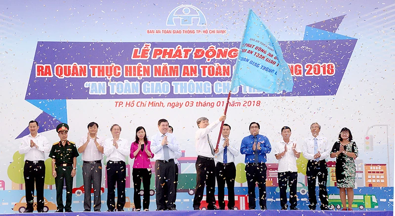 Chủ tịch UBND TPHCM Nguyễn Thành Phong trao cờ phát động ra quân thực hiện năm An toàn giao thông 2018. Ảnh: QUỐC HÙNG