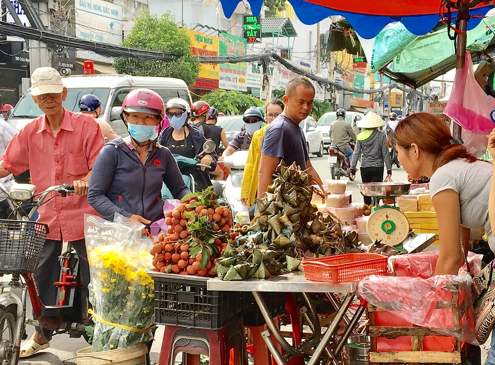 Khách hàng chọn mua bánh ú, trái cây sát chợ Hòa Hưng, quận 10, TPHCM, sáng 18-6. Ảnh: THI HỒNG