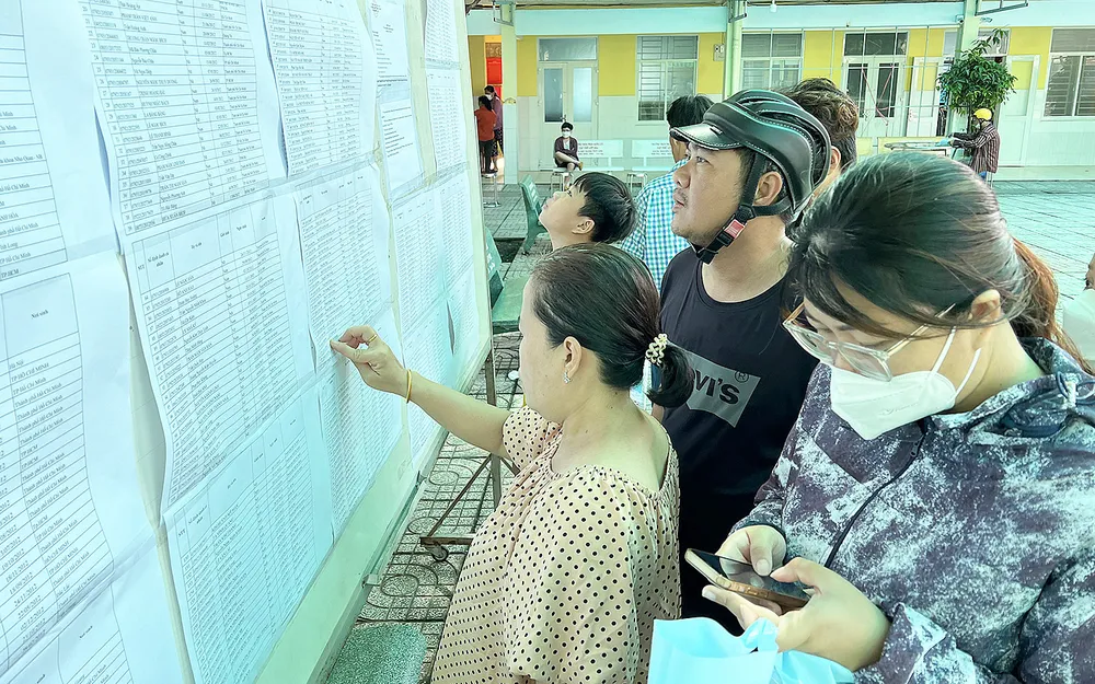 Phụ huynh xem danh sách học sinh lớp 6 năm học 2023-2024 tại Trường THCS Phan Đăng Lưu, quận 8, TPHCM. Ảnh: CAO THĂNG