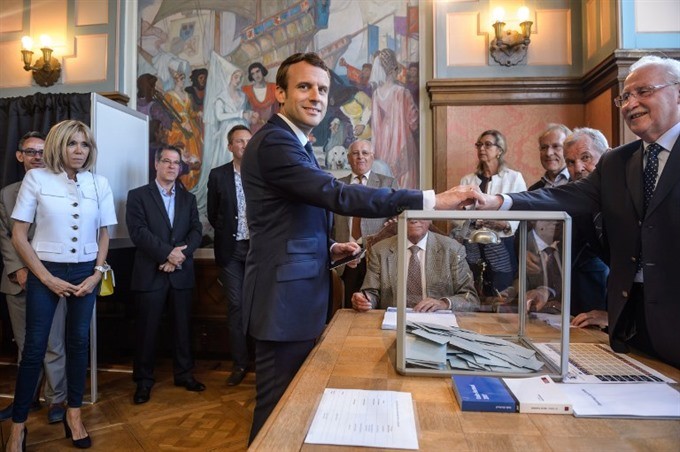 French President Emmanuel Macron (centre) casts his ballot next to his wife Brigitte Macron (left) at a polling station during the first round of the French legislative elections in Le Touquet, on June 11, 2017. — AFP/VNA