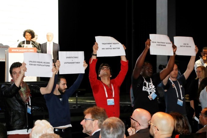 People hold placards during the opening of the 9th International AIDS Society conference on HIV Science on July 23, 2017, in Paris. — AFP/VNA 