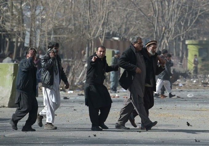 Volunteers help injured men at the scene where an ambulance exploded in front of the old Ministry of Interior building in Kabul on Saturday. — AFP/VNA Photo 