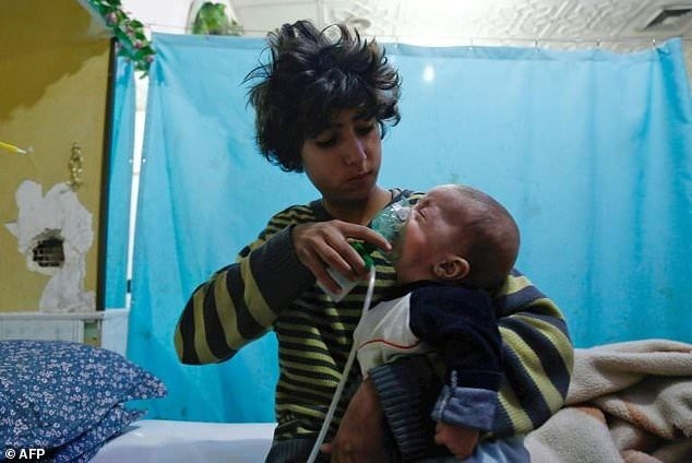 A Syrian boy holds an oxygen mask over an infant’s face at a makeshift hospital in Eastern Ghouta, where three reported chlorine attacks have occurred in recent weeks. - AFP/VNA Photo