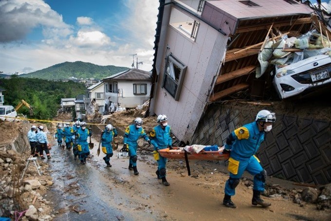 In one part of Kumano, Japan, the nose of a white car was just visible underneath the top floor of a home that had been torn from the rest of the building and swept down a hillside by floods. — AFP/VNA Photo