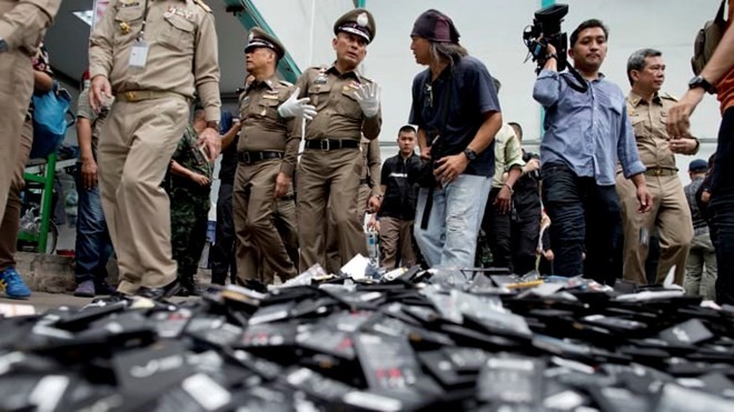 hai National Deputy Police Chief Wirachai Songmetta, centre with white gloves, law-enforcement officers and journalists walk past a pile of mobile batteries during a recent raid in Bangkok. (Photo: AP)