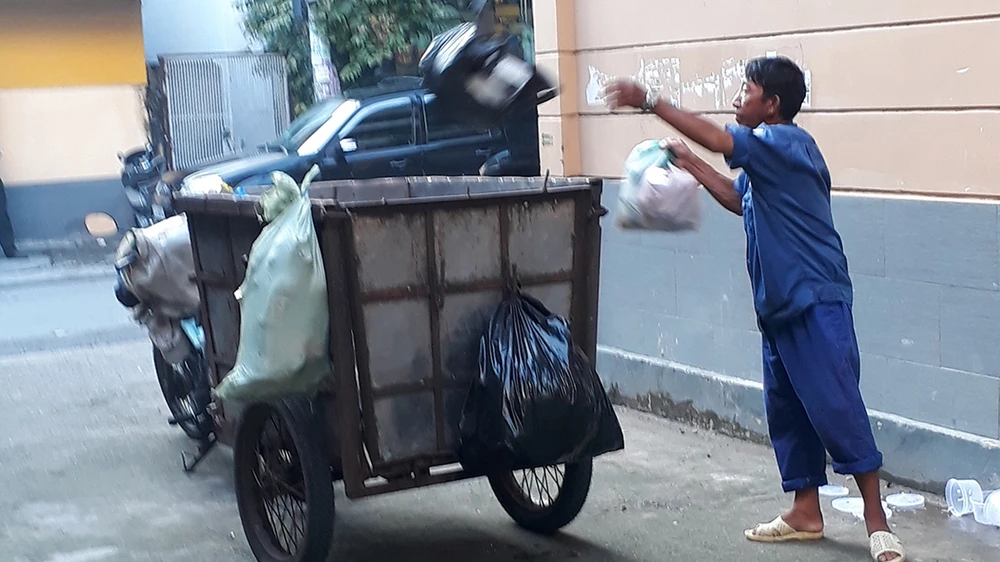 Người thu gom rác dân lập không trang bị bảo hộ lao động với chiếc xe lấy rác rất lạc hậu