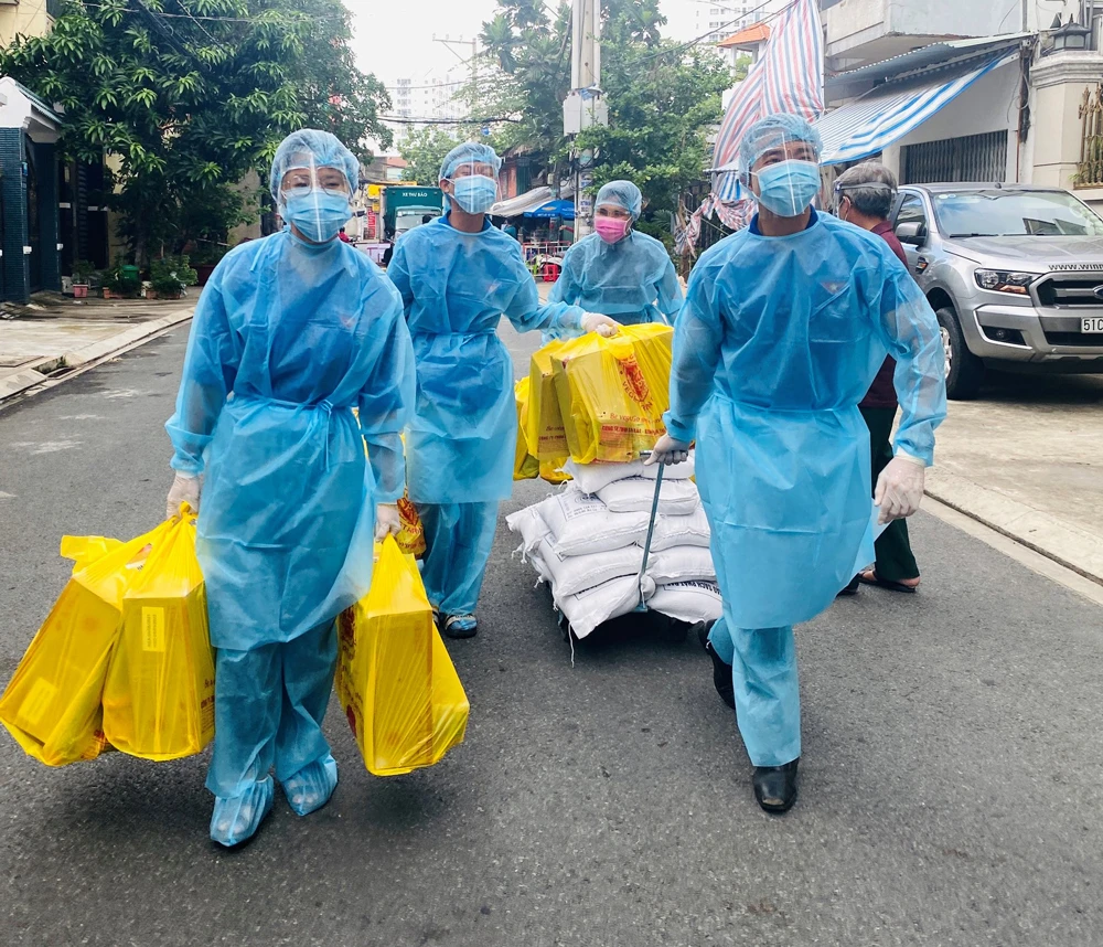 Đoàn viên thanh niên khu phố 1, phường Hòa Thạnh, quận Tân Phú đưa nhu yếu phẩm vào khu phong tỏa, trao tận tay người dân. Ảnh: VŨ TÂN