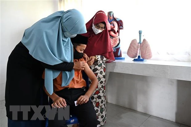 Nhân viên y tế tiêm vaccine phòng Covid-19 cho học sinh tại Indonesia. Ảnh: TTXVN