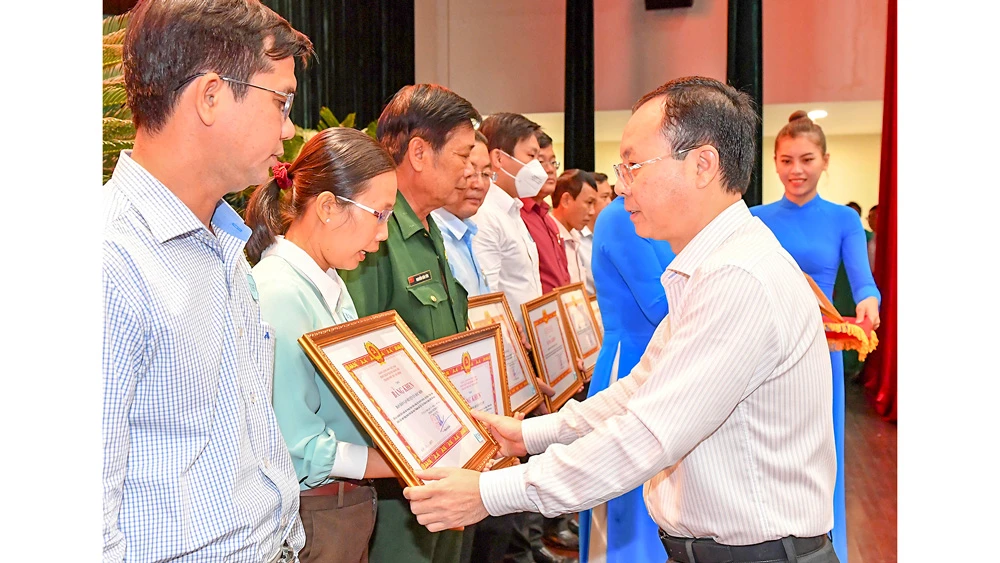 Phó Bí thư Thành ủy TPHCM Nguyễn Văn Hiếu tặng bằng khen cho các tập thể làm tốt công tác hiến đất mở rộng hẻm. Ảnh: VIỆT DŨNG