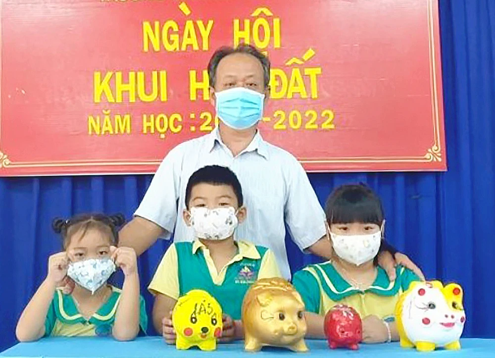 Thầy Nguyễn Phúc Hiếu và học sinh Trường Mầm non An Phú trong Ngày hội Khui heo đất