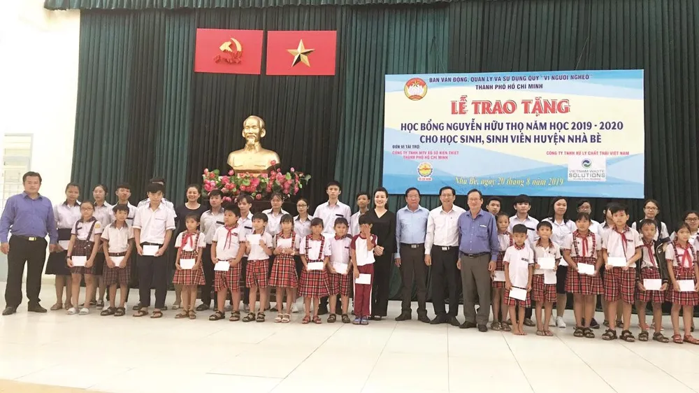 Ông Lê Văn Công, Kiểm Soát viên Công ty TNHH Một thành viên Xổ số kiến thiết TP Hồ Chí Minh cùng với lãnh đạo UBMTTQ TP, UBMTTQ huyện Nhà Bè và đơn vị Tài trợ chụp hình lưu niệm cùng với các em học sinh, sinh viên nhận học bổng