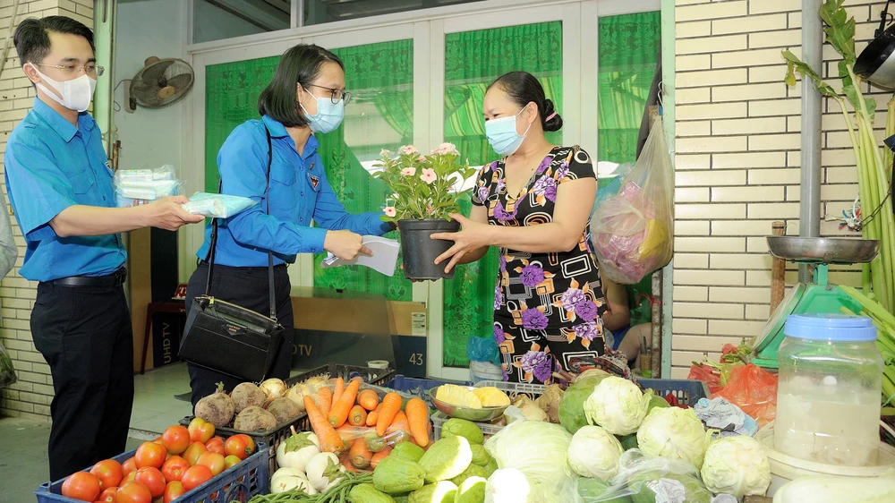 Tặng hoa, khẩu trang cho người dân tại các chợ. Ảnh: QUỐC THANH