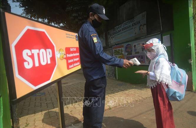 Kiểm tra thân nhiệt của học sinh để phòng dịch COVID-19 tại trường học ở Jakarta, Indonesia, ngày 30-8. Ảnh: TTXVN