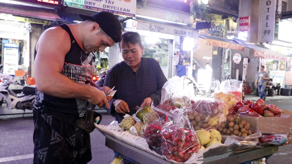 Du khách mua hàng rong tại phố đi bộ Bùi Viện, quận 1, TPHCM