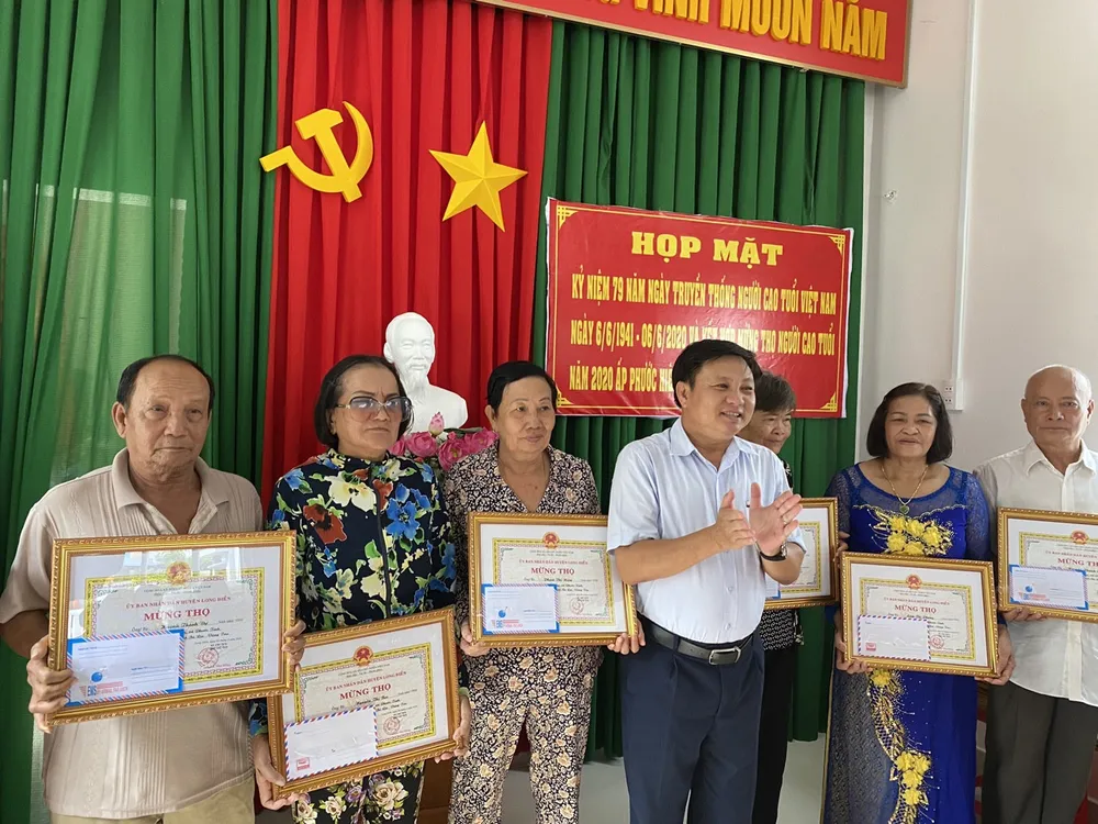 Ông Nguyễn Văn Nhỏ (đứng giữa), trao quà mừng thọ người cao tuổi ở ấp Phước Hiệp nhân Ngày truyền thống Người cao tuổi Việt Nam