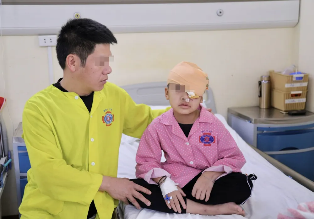 Bệnh nhi Đ. sau khi được phẫu thuật cắt bỏ khối u ở mắt, được cha chăm sóc ở bệnh viện