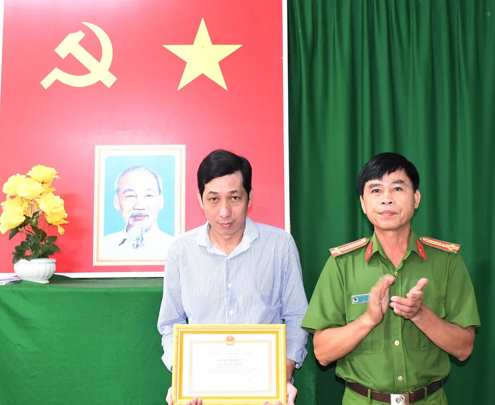Thượng tá Nguyễn Thành Thạnh, Phó trưởng phòng Phòng Cảnh sát PCCC-CNCH trao tặng giấy khen của Giám đốc Công an tỉnh cho anh Lê Thanh Hải. Ảnh: HỒ GIANG