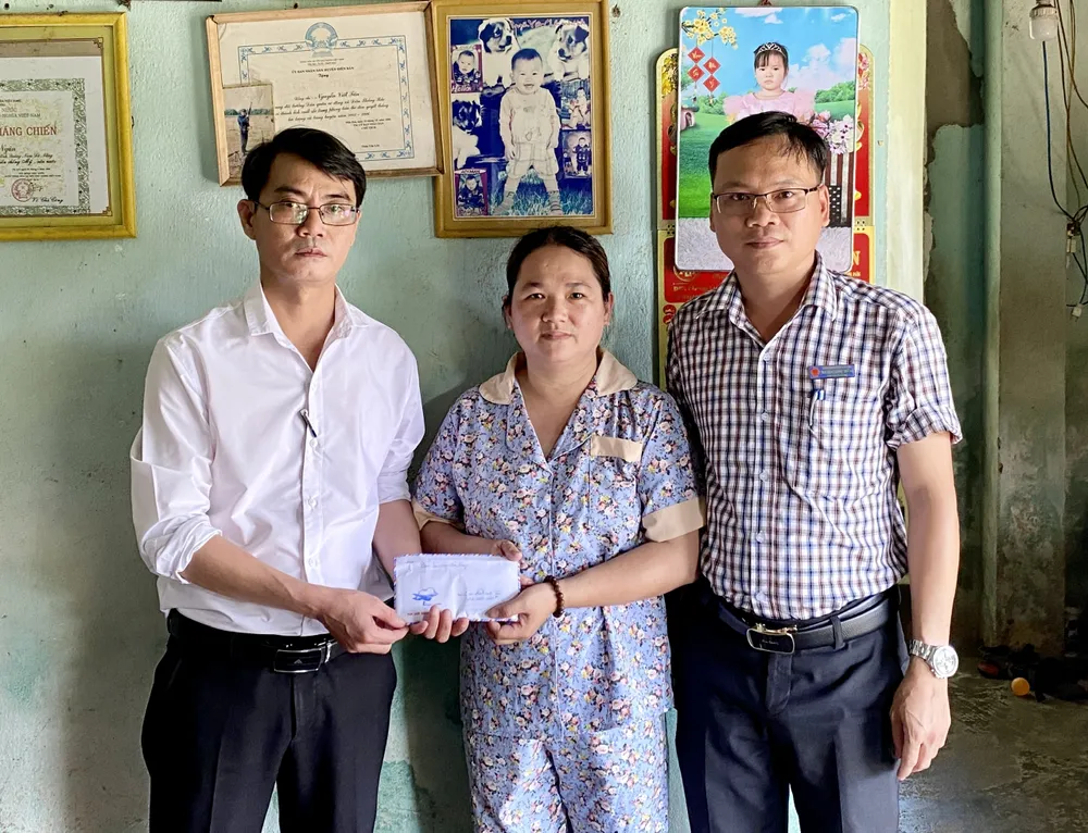 Nhà báo Nguyễn Hùng (Trưởng đại diện Báo SGGP tại miền Trung) trao 24 triệu đồng tiền hỗ trợ cho chị Võ Thị Lắm (vợ anh Nguyễn Viết Tân)