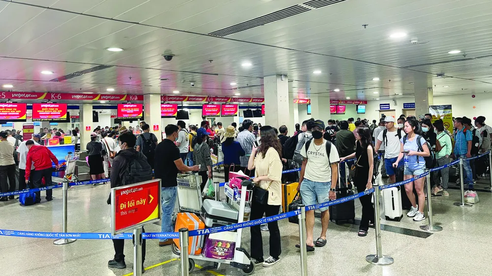 Hành khách xếp hàng chờ làm thủ tục tại sân bay Tân Sơn Nhất. Ảnh: HOÀNG HÙNG Hành khách xếp hàng chờ làm thủ tục tại sân bay Tân Sơn Nhất. Ảnh: HOÀNG HÙNG