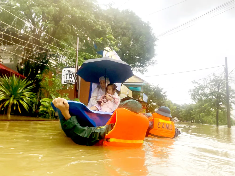 Chiến sĩ Công an TP Huế (Thừa Thiên Huế) kéo thuyền di chuyển sản phụ vượt lũ đi sinh. Ảnh: VĂN THẮNG