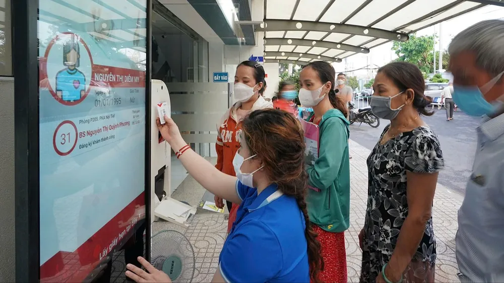 Nhân viên y tế Bệnh viện Thống Nhất TPHCM hướng dẫn người dân quẹt thẻ Tekmedi để đăng ký khám chữa bệnh. Ảnh: HOÀNG HÙNG T4c.jpg