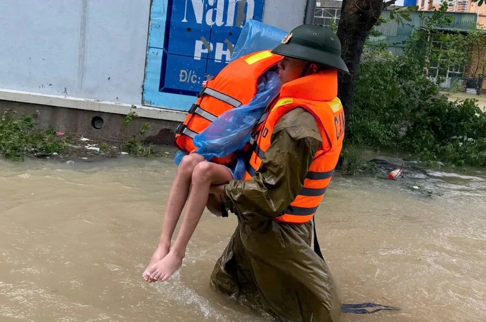 Policjanci prowincji Thanh Hoa wynoszą dziecko z niebezpiecznego obszaru powodziowego w gminie Ngoc Lac. PSA Anh15-cường 1.jpg