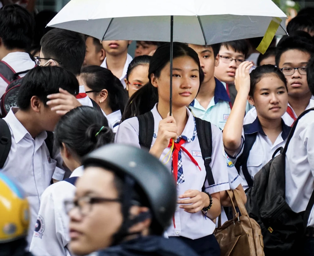 Thí sinh kết thúc thi môn Anh văn tại điểm thi Trường THCS ra về trong cơn mưa tầm tã