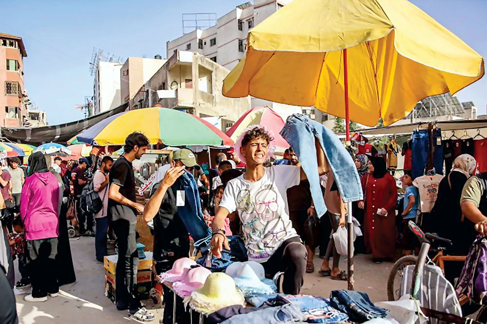 Một cậu bé bán quần áo trên một con phố chợ đông đúc ở Thành phố Gaza vào ngày 15-6. Ánh: Omar Al-Qattaa/AFP