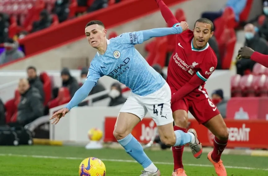 Phil Foden (trái) đi bóng qua Thiago 