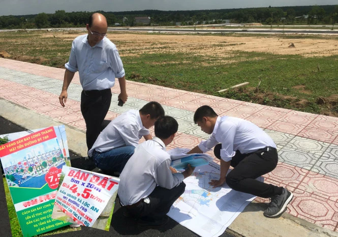 Nhân viên môi giới trải sơ đồ quy hoạch sử dụng đất quanh khu sân bay Long Thành, giới thiệu cho khách hàng khu đất bán trên đường ĐT 769, huyện Long Thành, tỉnh Đồng Nai. Ảnh nhỏ: những tấm biển rao bán đất gần sân bay Long Thành - Ảnh: QUANG ĐỊNH