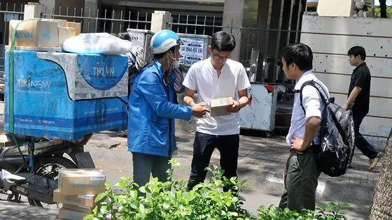 Nhận hàng đặt mua qua thương mại điện tử. Ảnh: THÀNH TRÍ