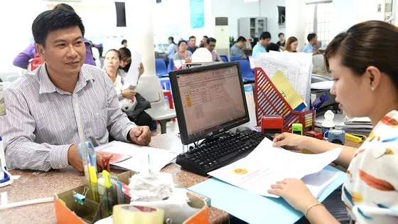  Người dân làm thủ tục hành chính tại bộ phận một cửa UBND huyện Hóc Môn. Ảnh: QUANG HUY 
