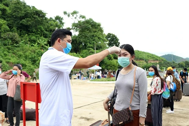 Lực lượng chức năng kiểm tra thân nhiệt lưu học sinh Lào tại cửa khẩu Chiềng Khương, tỉnh Sơn La. (Ảnh: Hữu Quyết/TTXVN)