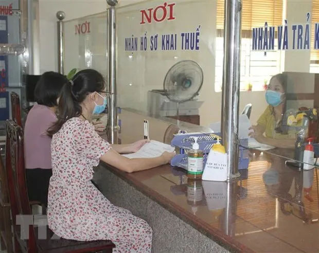 Cán bộ ngành thuế tuyên truyền, hướng dẫn người nộp thuế bị ảnh hưởng bởi dịch COVID-19. (Ảnh: Thùy Dung/TTXVN)