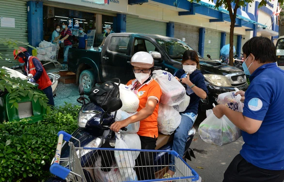 Chị Giang Thị Bích Hà (trái) - chủ tịch Hội LHPN phường 1, quận 3 - cùng tình nguyện viên giao hàng mua hộ cho dân - Ảnh: T.T.D.