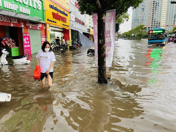 Người dân Hà Nội vất vả di chuyển trong cơn ngập lịch sử chiều 29-5 - Ảnh: QUANG THẾ