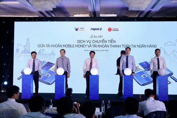 Các đại biểu thực hiện nghi thức ra mắt dịch vụ chuyển tiền giữa tài khoản Mobile Money và tài khoản thanh toán ngân hàng. (Ảnh: Vietnam+)