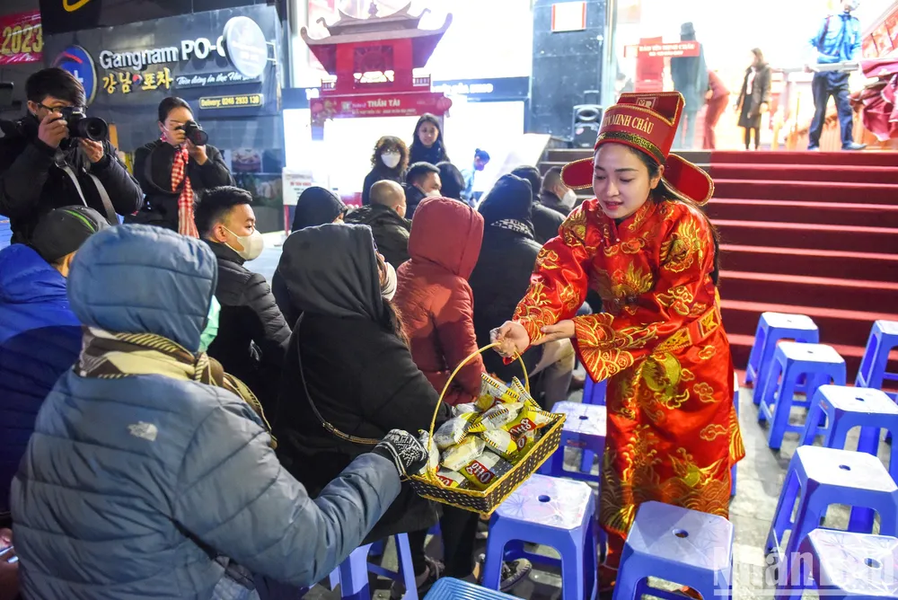 Nhân viên trong trang phục Thần Tài tặng bánh cho khách hàng trong thời gian chờ đợi.