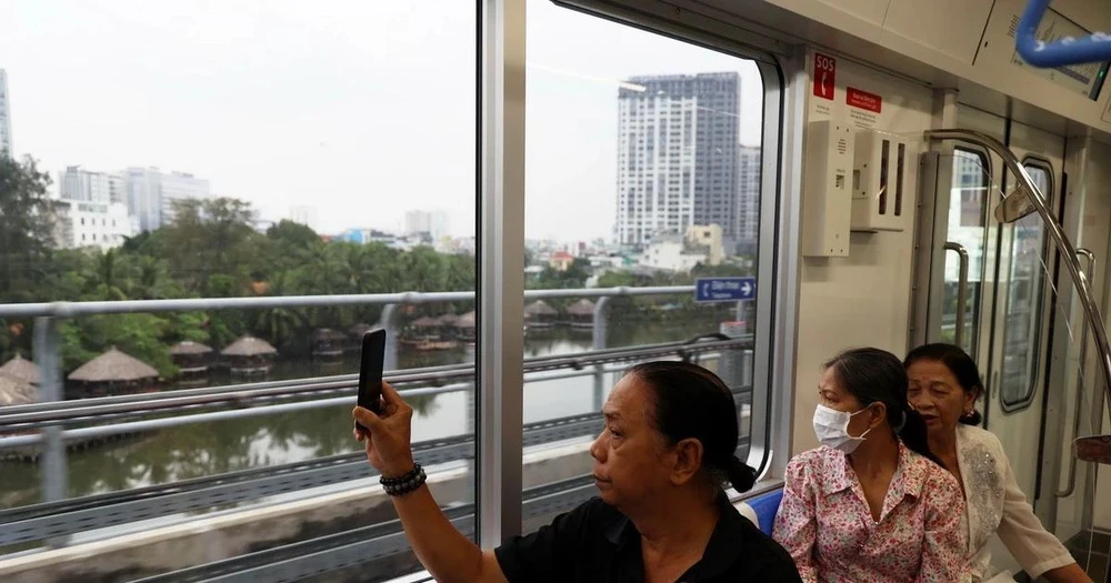 Người dân lưu lại hình ảnh đô thị bên ngoài khi trải nghiệm tuyến metro số 1. (Ảnh: Huyền Trinh/TTXVN)