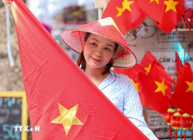 Người dân lưu lại khoảnh khắc với hình ảnh cờ Tổ quốc. (Ảnh: Khánh Hòa/TTXVN)