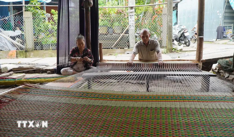 Gia đình ông Huỳnh Văn Chiến là một trong số ít hộ dân ở làng chiếu Định Yên còn dệt chiếu thủ công để giới thiệu nghề truyền thống với khách du lịch. (Ảnh: Nhựt AnTTXVN)