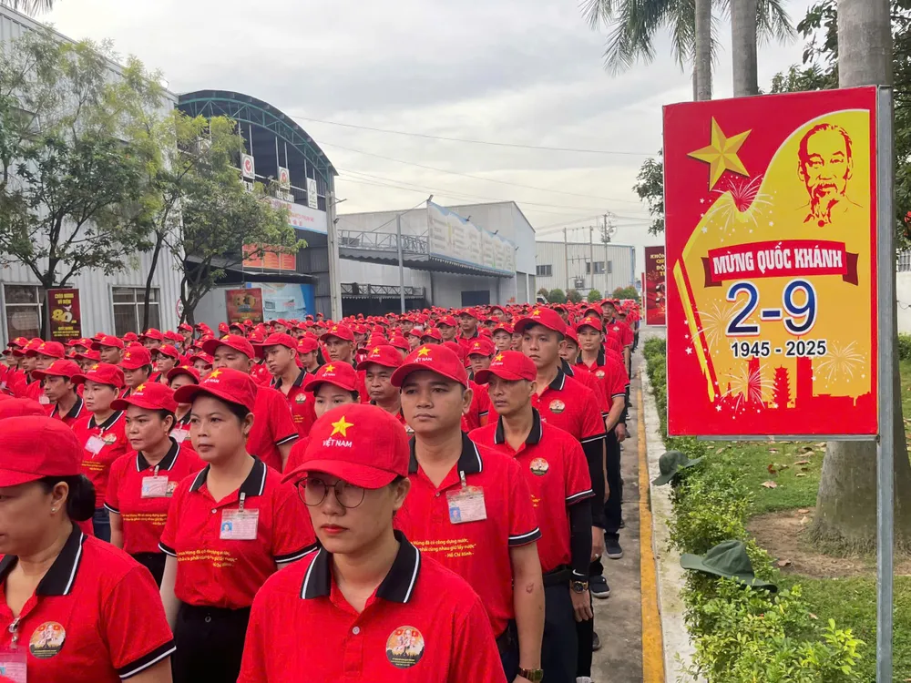Hàng trăm lao động công ty trong trang phục màu đỏ và ngôi sao vàng trên mũ, chỉnh tề hát quốc ca. Ảnh: XUÂN TRUNG 222.jpg