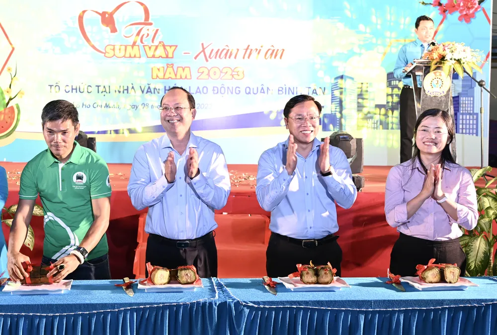 Phó Bí thư Thành ủy TPHCM Nguyễn Hồ Hải và Bí thư Quận ủy quận Bình Tân Huỳnh Khắc Điệp cắt bánh tét khai xuân. Ảnh: VĂN MINH