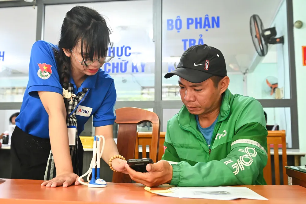 Thanh niên tình nguyện hỗ trợ người dân tại Trung tâm Phục vụ hành chính công phường. Ảnh: VIỆT DŨNG 67060873290c9f52c61d.jpg