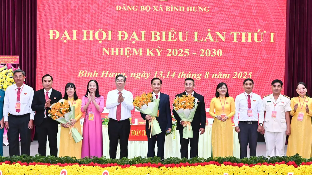 Đồng chí Nguyễn Phước Lộc và đồng chí Võ Ngọc Thanh Trúc tặng hoa chúc mừng Ban Chấp hành Đảng bộ xã Bình Hưng. Ảnh: VIỆT DŨNG IMG_0554.jpeg