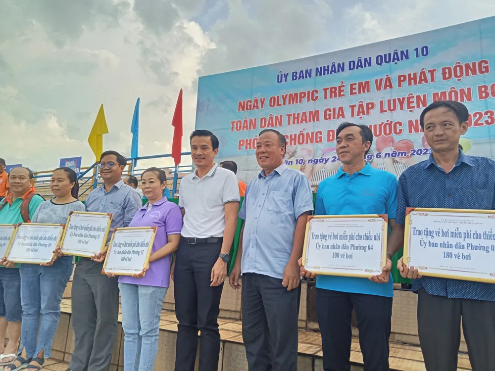 Ông Nguyễn Nam Nhân, Phó Giám đốc Sở Văn hóa và Thể thao TPHCM và ông Bùi Thế Hải trao tặng vé bơi miễn phí cho thiếu nhi trên địa bàn quận 10