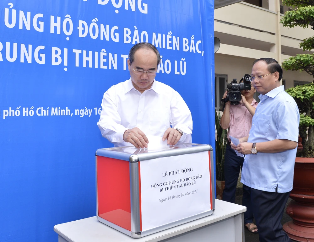 Bí thư Thành ủy TPHCM Nguyễn Thiện Nhân và Phó Bí thư Thường trực Thành ủy TP Tất Thành Cang đóng góp ủng hộ đồng bào vùng lũ. Ảnh: VIỆT DŨNG