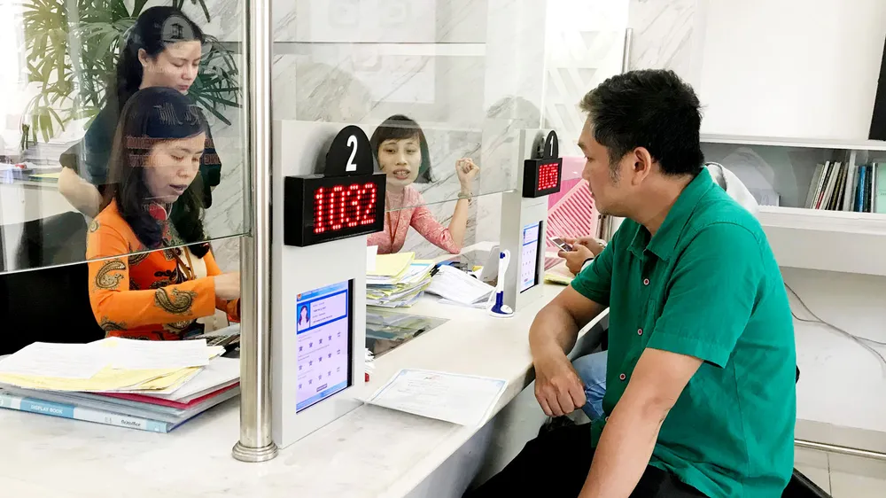 Sở Nội vụ TPHCM đề xuất quy định nữ công chức khi tiếp dân phải mặc quần tây hoặc váy dài qua đầu gối, áo sơmi có tay hoặc comple hoặc bộ áo dài truyền thống. Trong ảnh là công chức quận 1 giải quyết thủ tục cho dân. Ảnh: KP