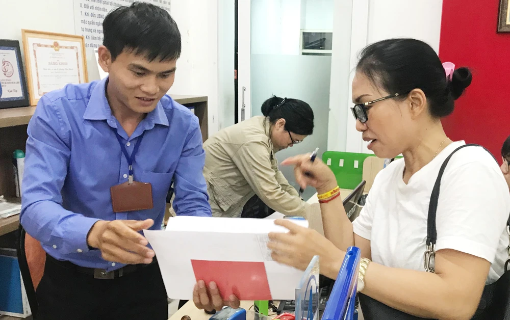 Công chức phường Bến Thành, quận 1, TPHCM đang tiếp nhận, chứng thực hồ sơ sao y của người dân ngoài giờ hành chính. Ảnh: KIỀU PHONG